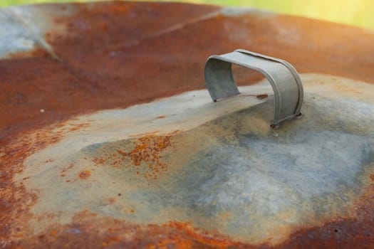 Rusty upturned lid in garden close up.