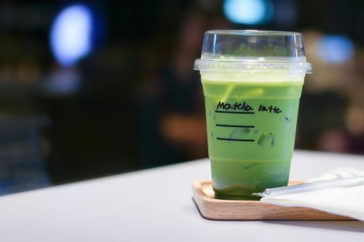 Iced matcha green tea latte on table in store.