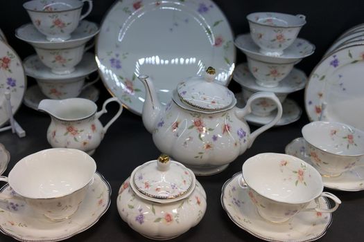 porcelain tea and white dining set with a delicate flower pattern, standing on a dark background