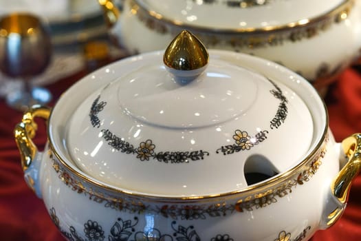 Background with white porcelain tableware with floral ornament and gilded details.