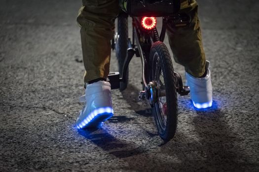 feet in shining shoes on the bike in the evening on the background of the road.