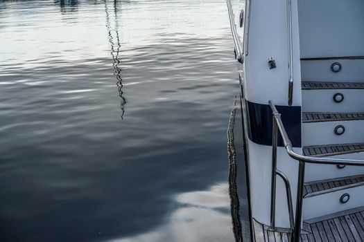 Details of the hull of a white yacht on the background of the water surface