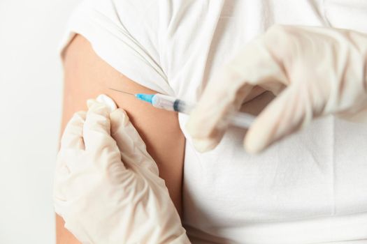 a doctor with gloves injecting an injection into the shoulder close-up. High quality photo