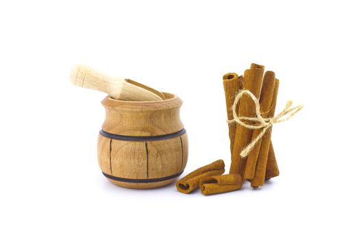 Cinnamon sticks bundle tied with jute string and a small wooden pot isolated on white background