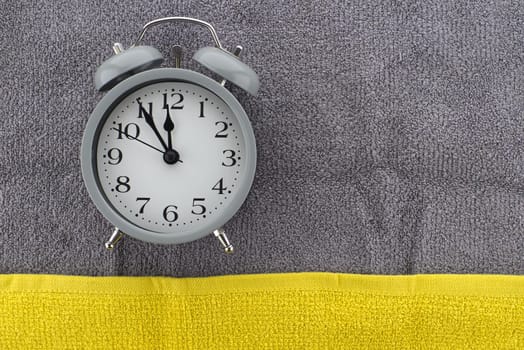 Vintage alarm clock on a two tone grey and yellow textile background with copy space viewed as a flat lay. Color of the year and color trends concept