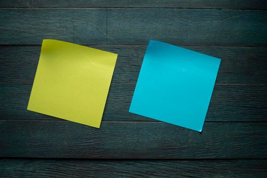 Blank color paper adhesive note stickers with curled corners on blue rustic board. Free copy space for text