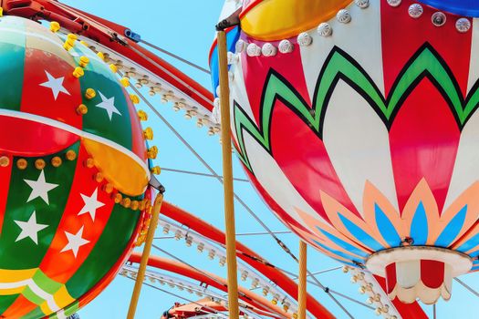 close up image of Ferris wheel with multi-coloured cabins against the sky.