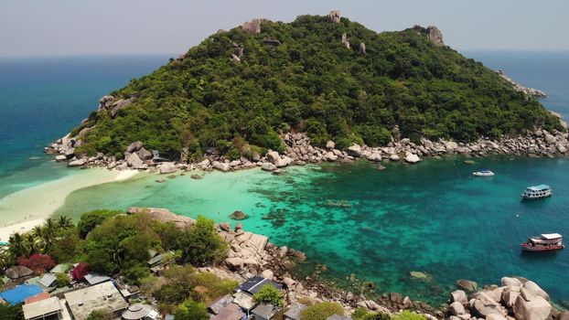 Boats near small islands. Motor dive boats floating on calm blue sea near unique small islets connected with white beaches and pier on sunny day in Thailand. Unique Nang yuan koh tao