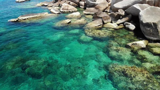 Calm sea water near stones. Peaceful blue sea water and gray boulders in perfect place for snorkeling on Koh Tao Island on sunny day in Thailand. Natural background texture