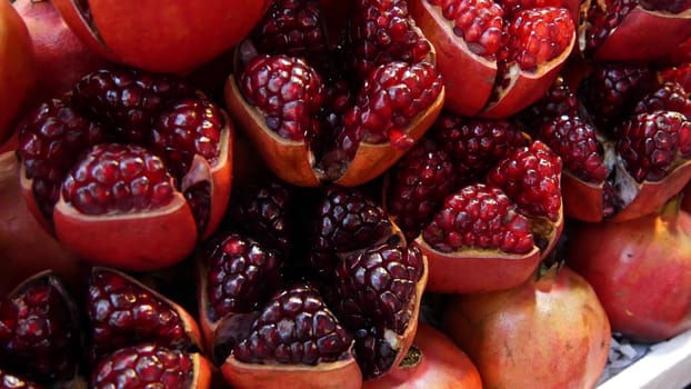 Halves of ripe pomegranates for juice. Heap of halves of yummy ripe pomegranates for fresh juice placed on stall.