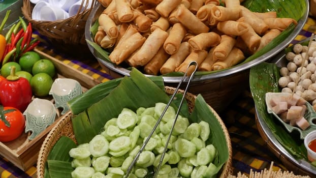 Bowls with traditional Asian dishes for sale. Bowls with fresh vegetables and fried spring rolls placed on stall of traditional street diner in Thailand