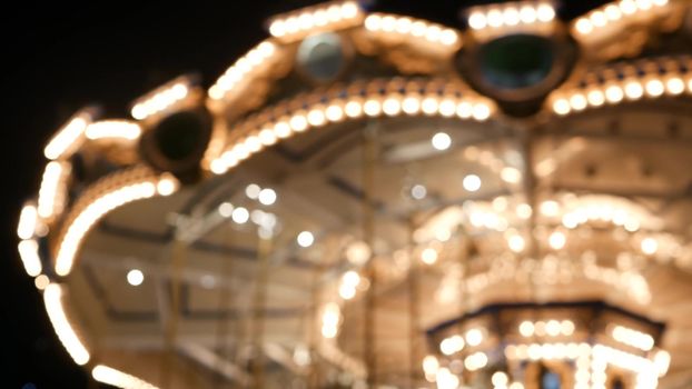 Illuminated blurred merry go round in park. Brightly illuminated roundabout spinning in wonderful amusement park at night.