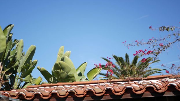 Mexican colonial style suburban, hispanic house exterior, green lush garden, San Diego, California USA. Mediterranean terracotta ceramic clay tile on roof. Rustic spanish tiled rooftop. Rural details.