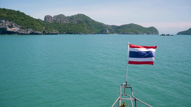 Group of Islands in ocean at Ang Thong National Marine Park. Archipelago in the Gulf of Thailand. Idyllic turquoise sea natural background with copy space. Waving flag as national symbol on the boat