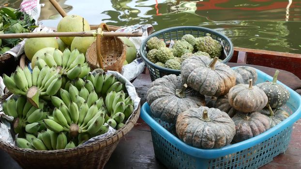 Iconic asian Lat Mayom floating market. Khlong river canal, long-tail boat with tropical exotic colorful fruits, organic locally grown vegetables. Top view of harvest and street food in wooden canoe.