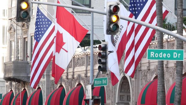 World famous Rodeo Drive Street Road Sign in Beverly Hills against American Unated States flag. Los Angeles, California, USA. Rich wealthy life consumerism, Luxury brands, high-class stores concept