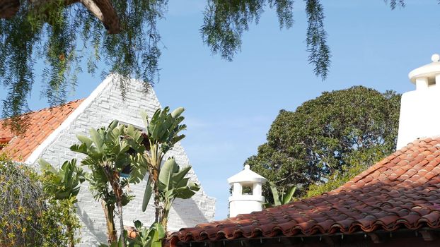 Mexican colonial style suburban, hispanic house exterior, green lush garden, San Diego, California USA. Mediterranean terracotta ceramic clay tile on roof. Rustic spanish tiled rooftop. Rural details.