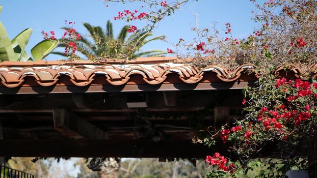 Mexican colonial style suburban, hispanic house exterior, green lush garden, San Diego, California USA. Mediterranean terracotta ceramic clay tile on roof. Rustic spanish tiled rooftop. Rural details.