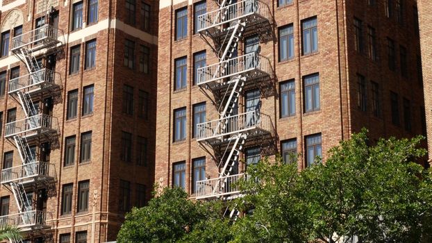 Fire escape ladder outside residential brick building in San Diego city, USA. Typical New York style emergency exit for safe evacuation. Classic retro house exterior as symbol of real estate property.