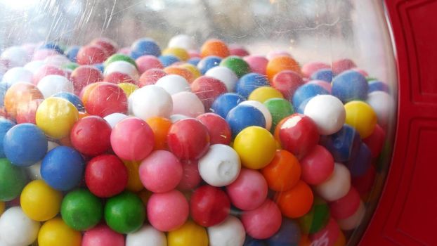 Colorful gumballs in classic vending machine, USA. Multi colored buble gums, coin operated retro dispenser. Chewing gum candies as symbol of childhood and summertime. Mixed sweets in vintage automate.