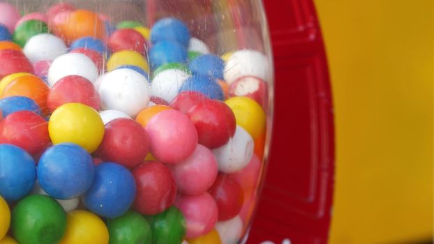 Colorful gumballs in classic vending machine, USA. Multi colored buble gums, coin operated retro dispenser. Chewing gum candies as symbol of childhood and summertime. Mixed sweets in vintage automate.