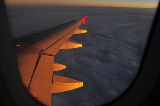 Golden light clouds from plane, View from plane in flight of majestic clouds in golden sunset light illuminating air.