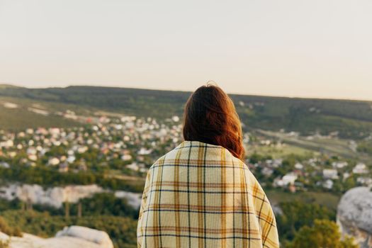 woman with a plaid on her shoulders in nature and buildings in the background. High quality photo