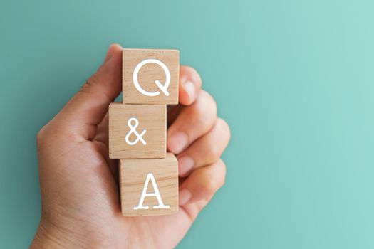 Q and A alphabet on wooden cube in hand hold with background. Question and answer meaning concept.