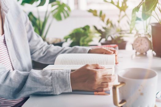 Woman is reading book in workspace area with nature background feeling relax and peaceful environment. Education business concept.