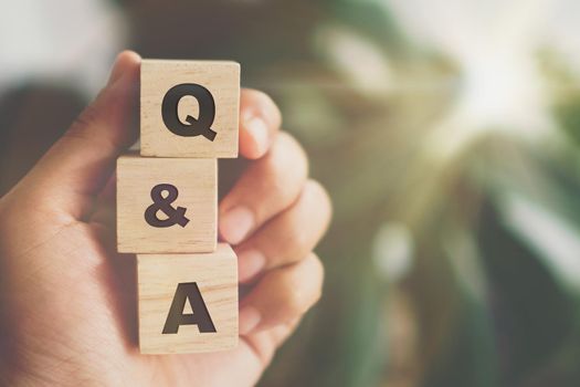 Q and A alphabet on wooden cube in hand hold with background. Question and answer meaning concept.