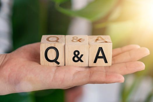 Q and A alphabet on wooden cube in hand hold with background. Question and answer meaning concept.