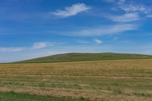 Natural landscape with hills against blue sky with white clouds.