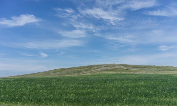 Natural landscape with hills against blue sky with white clouds.