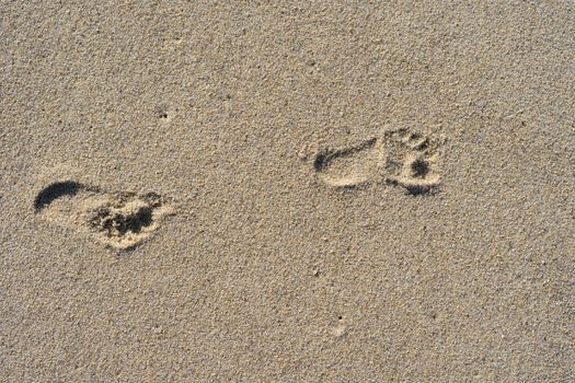 Natural background of sand with the prints of human feet