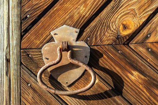 Metal door handle on the background of a wooden door.