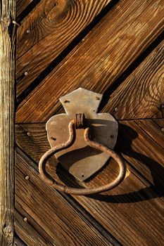 Rusty door handle on the background of the door of a wooden house.