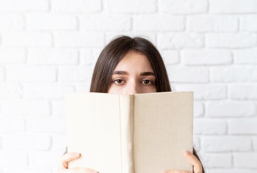 Close up of woman holding an opened book in front of her face