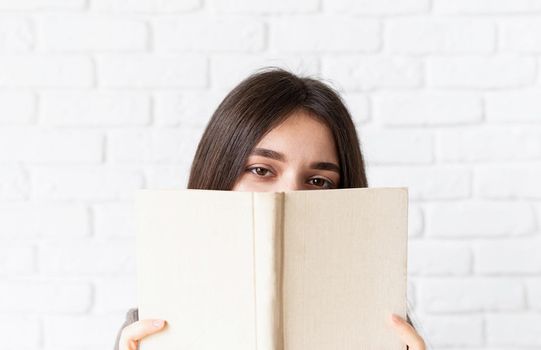 Close up of woman holding an opened book in front of her face