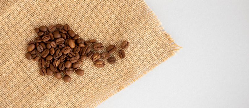 Coffee beans and burlap lie on a gray background.