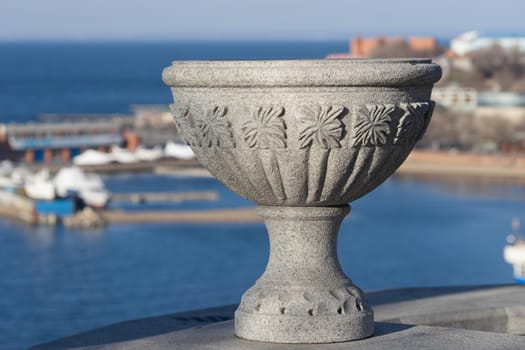 Decorative stone vase on the street of the city against the sea. Vladivostok, Russia.