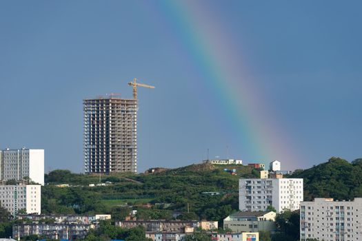 Urban landscape with a rainbow on the sky background. Vladivostok, Russia