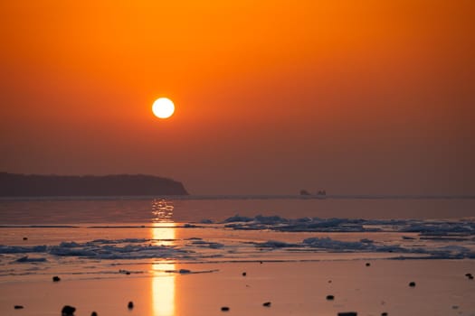 Seascape ice beach and the red sunset.