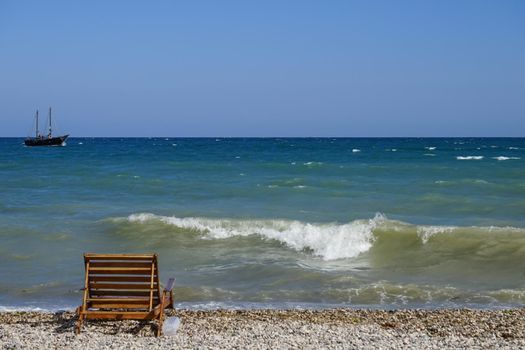 Seascape with a wooden bench and a ship on the horizon. Koktebel, Crimea