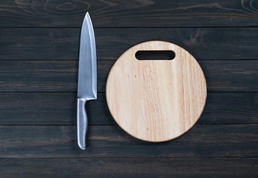 kitchen knife and wooden round empty cutting board on a wooden table close up