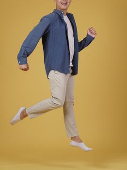 portrait of happy excited glad rejoicing joyful young asian man dressed casually jumping isolated on yellow studio background