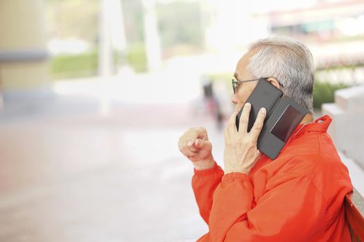 asian old asian elderly senior elder man talking on smart mobile phone outdoor