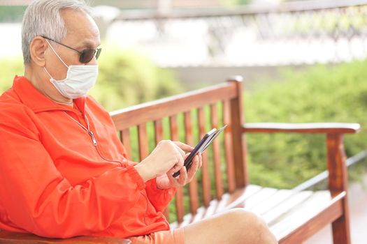 asian old elder senior man elderly male wearing face mask using mobile smart phone cellphone outdoor. mature retirement lifestyle