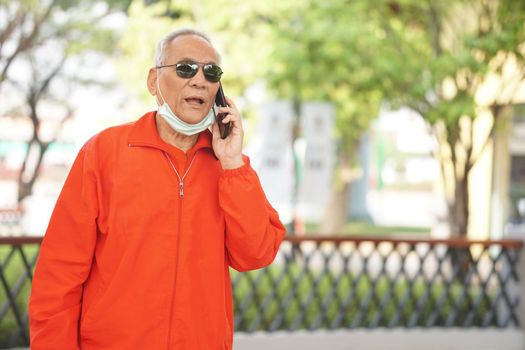 asian old asian elderly senior elder man talking on smart mobile phone outdoor