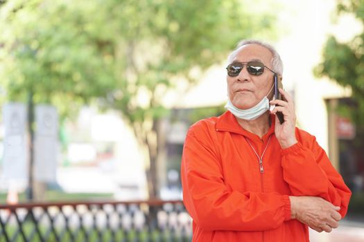 asian old asian elderly senior elder man talking on smart mobile phone outdoor
