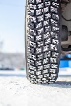 Car tires on the winter road are covered with snow. A car on a snow-covered alley. A car wheel in the snow.